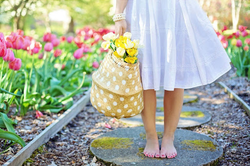 barefoot woman outside with a basket of flowers