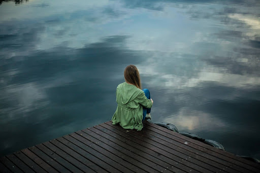 sad woman on pier looking out at the dark cold water
