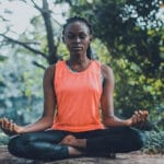 woman in orange tank top peacefully meditating