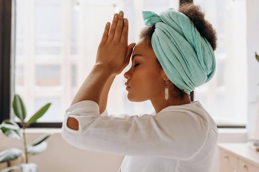 woman kneeling and praying with hands to forehead