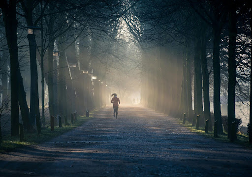 woman running outside in a park surrounded by trees