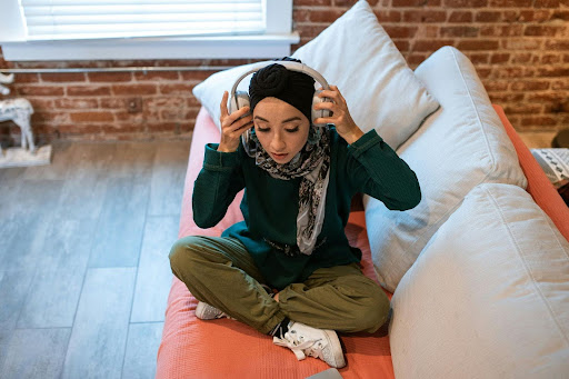 woman sitting cross legged on couch putting on headphones